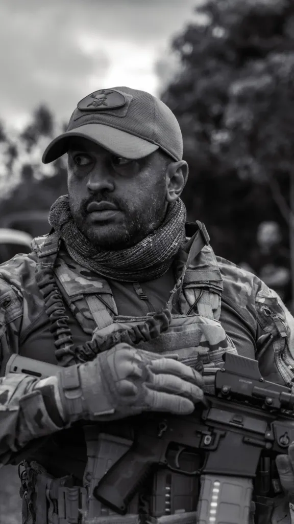 Douglas Pithon em retrato preto e branco, com boné e equipamento tático